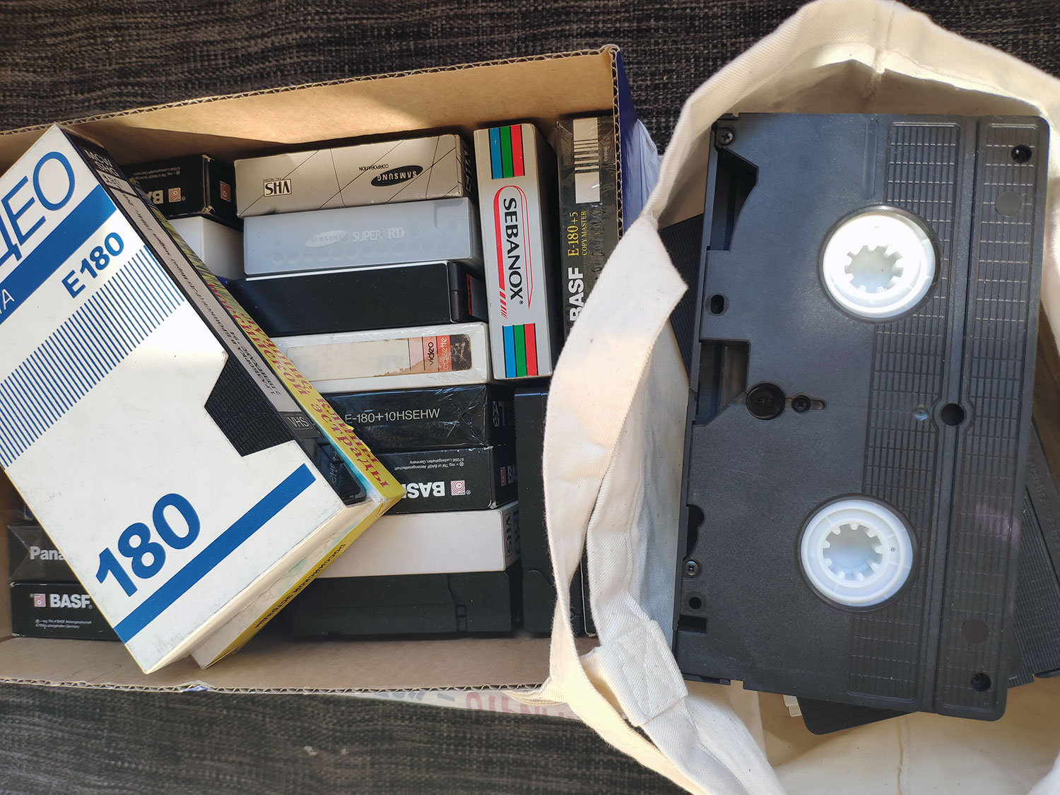 Коробка з відеокасетами VHS і тканинна торба з касетою — оцифрування сімейного архіву, Київ