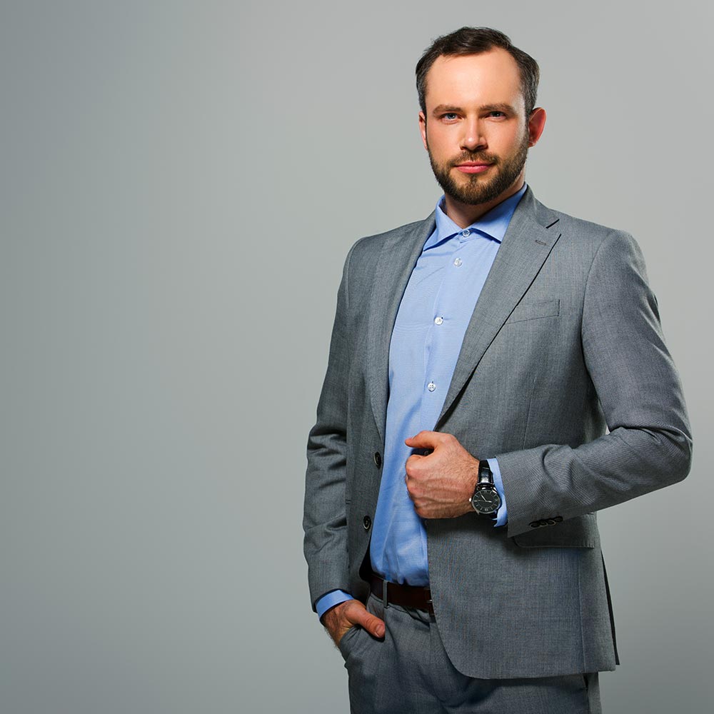 Молодий чоловік у сірому костюмі на сірому фоні — студійне бізнес-фото, Київ