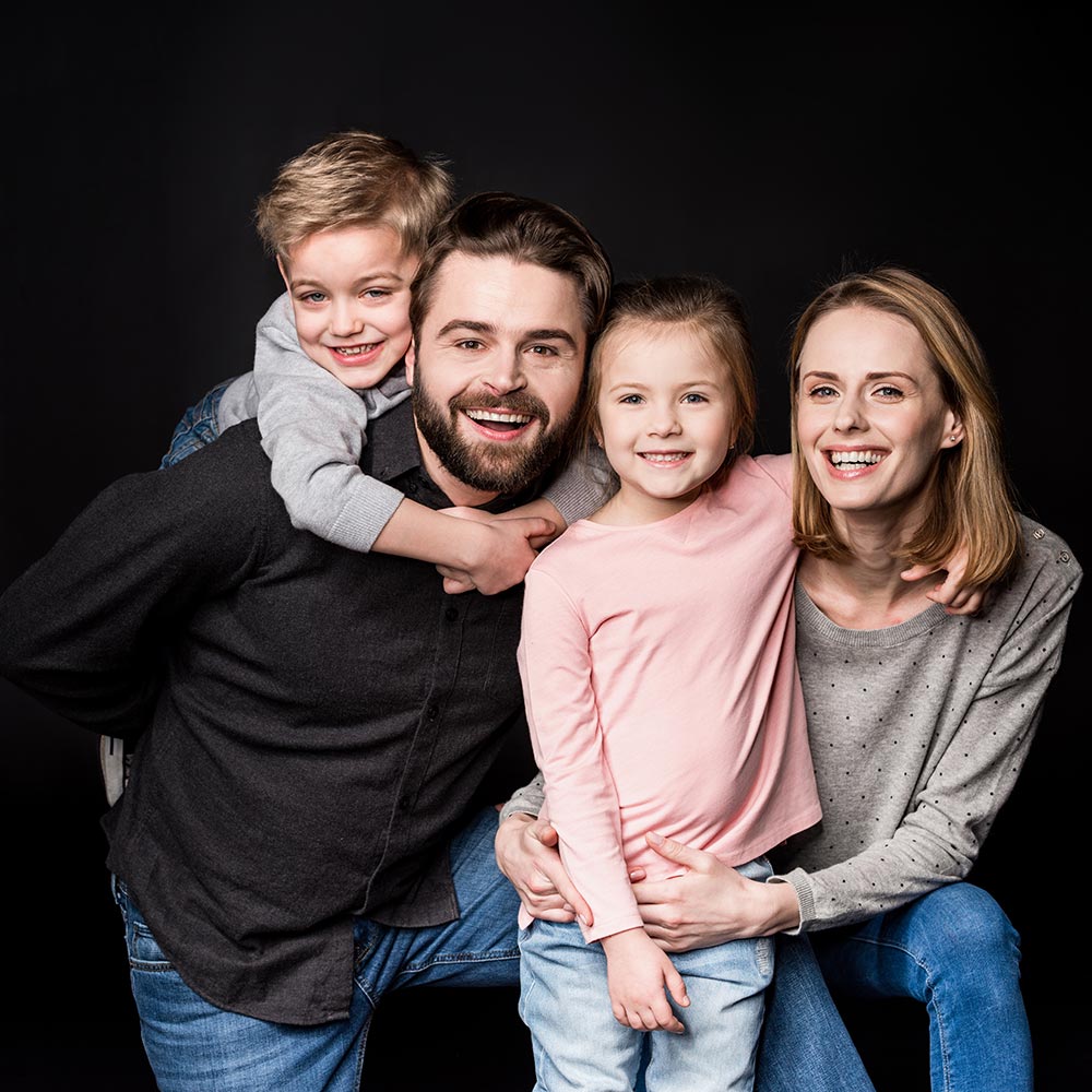 Щаслива сім’я з двома дітьми у студії — сімейна фотосесія на чорному фоні, Київ